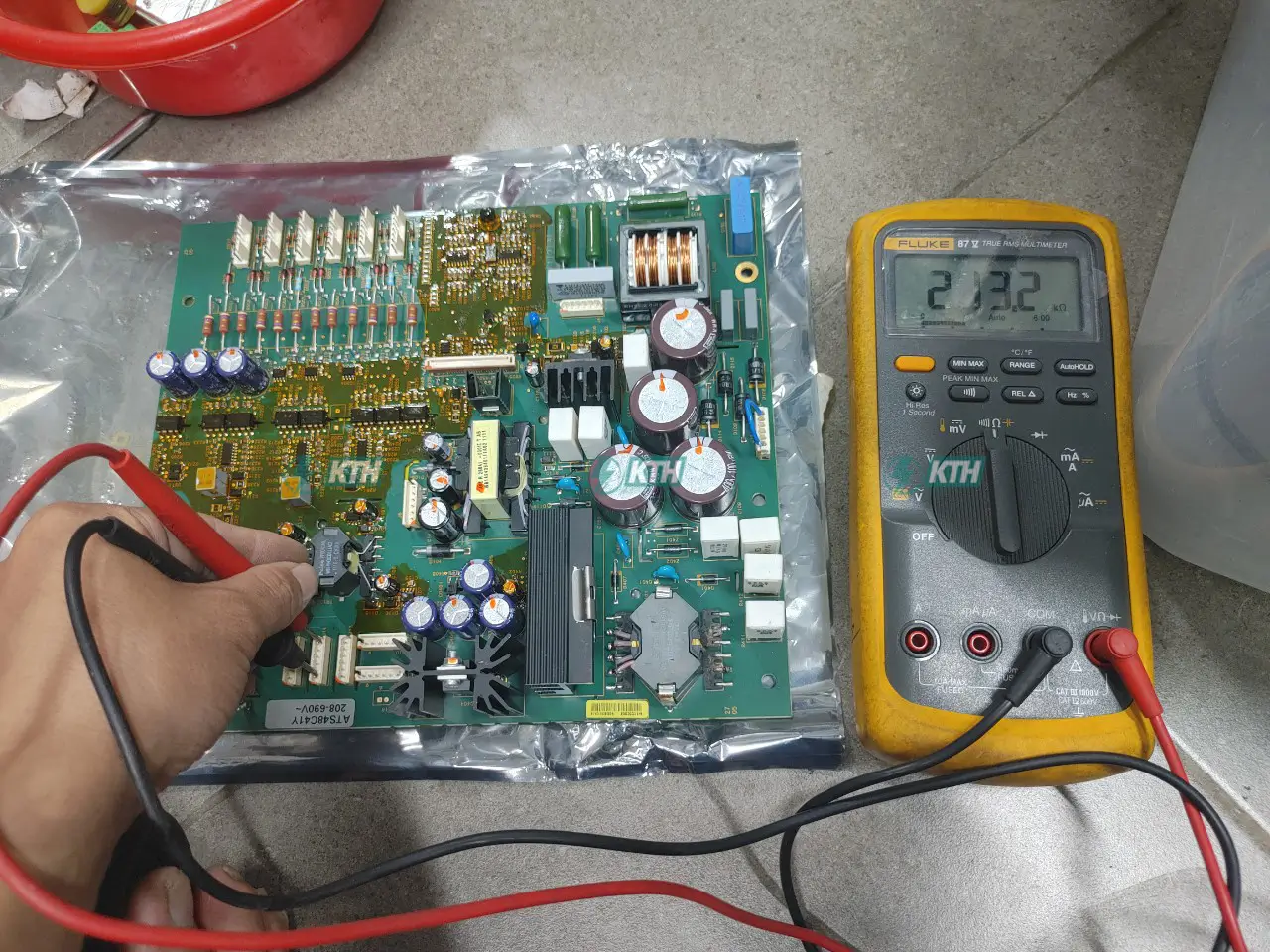 Kỹ thuật viên đang sửa chữa biến tần công nghiệp bằng đồng hồ vạn năng